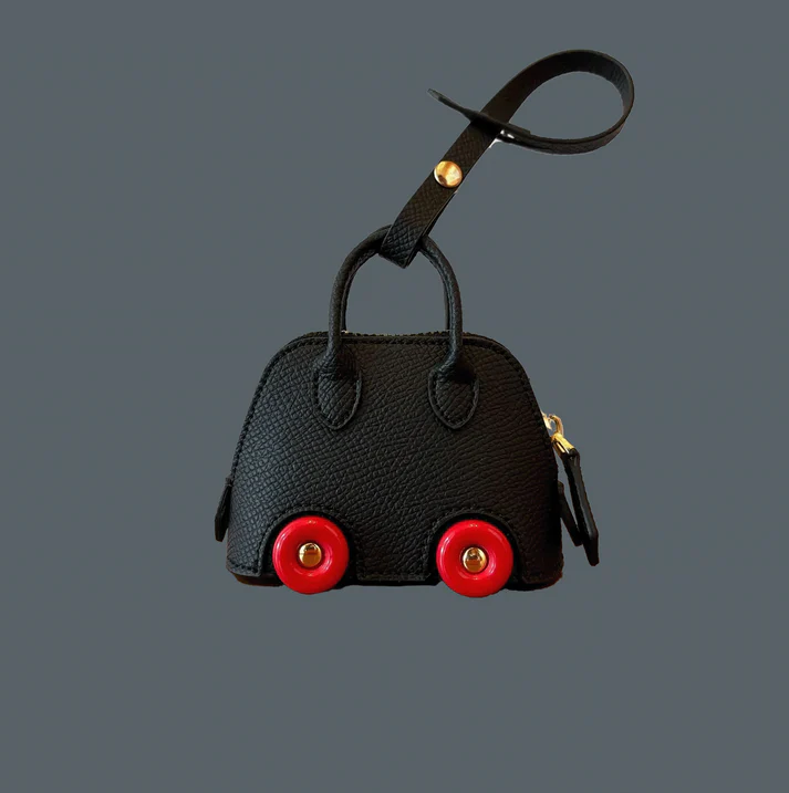 Close-up of the Bodile on Wheels Inspired Bag Charm, featuring a luxurious designer-inspired design with playful wheel details. Functional and stylish, perfect for storing small essentials like AirPods or keys, and adding a touch of elegance to any bag