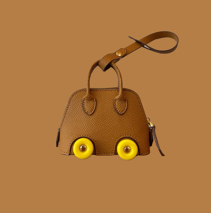 Close-up of the Bodile on Wheels Inspired Bag Charm, featuring a luxurious designer-inspired design with playful wheel details. Functional and stylish, perfect for storing small essentials like AirPods or keys, and adding a touch of elegance to any bag