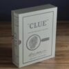 Elegant Clue Vintage Edition board game styled as a linen-bound book, with 1949-inspired graphics, metal weapons, wood tokens, and vintage clue cards.