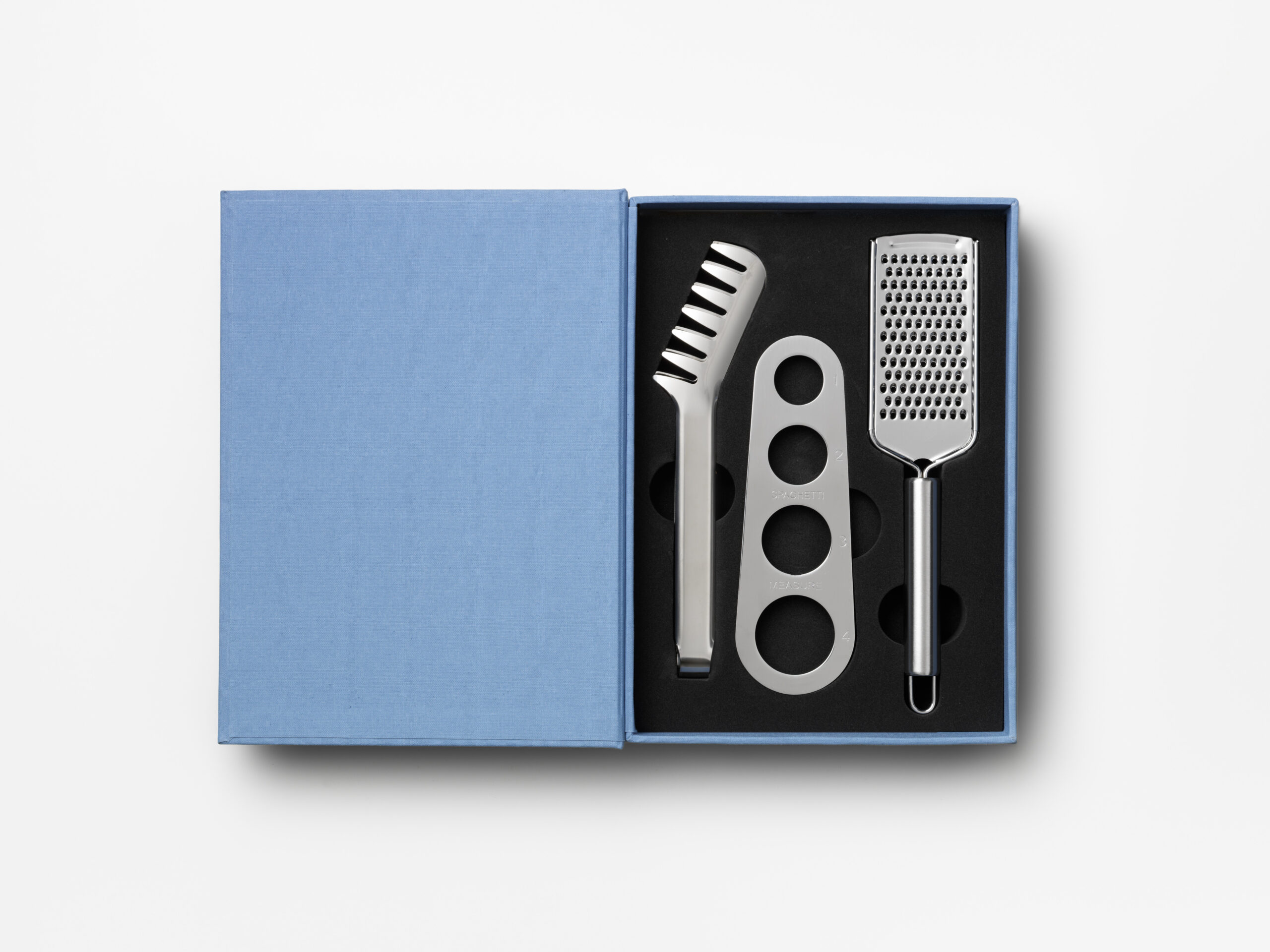 Pasta gift set in bright blue book-style box with stainless steel spaghetti measurer, tongs and grater – luxury gift open box