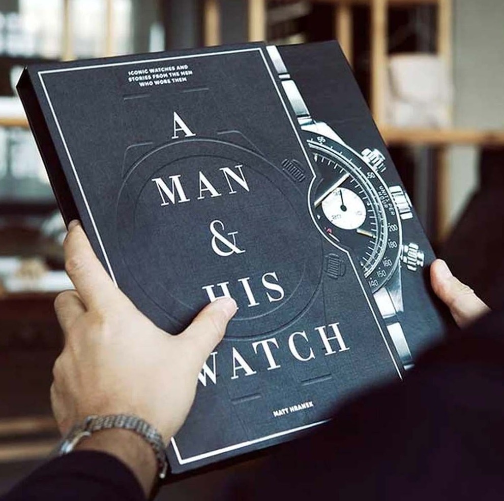 A man and his watch book from matt hranek out of book sleeve in the hands of a man