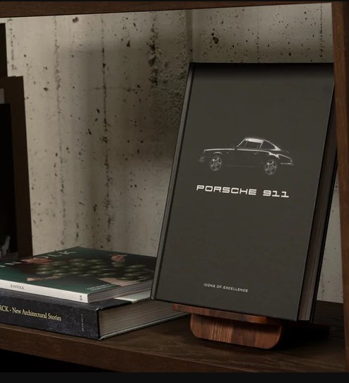 Porsche 911: Icons of Excellence — black hardcover luxury coffee table book with iconic Porsche photography on book stand on shelf